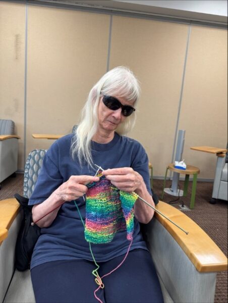 Judith Rasmussen sitting in a chair knitting