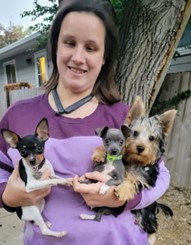 Meghan Whalen standing in front of a tree holding three small dogs