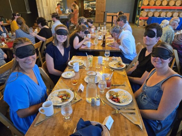 A roomful of people eating a meal while wearing blindfolds
