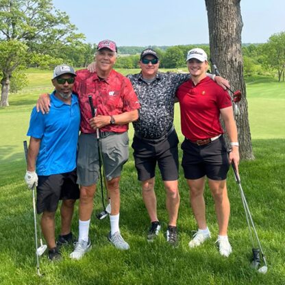 Four men wearing shorts and carrying golf clubs standing on a golf course