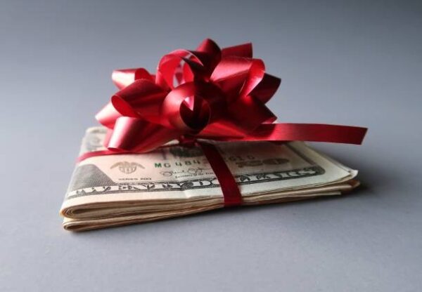 A folded pile of money tied with a red bow.