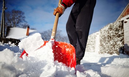 The bottom half of a person shoveling snow.