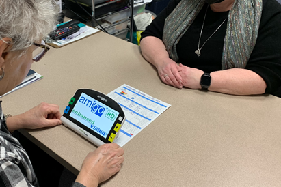 A person learning to use a digital magnifier to read a bill