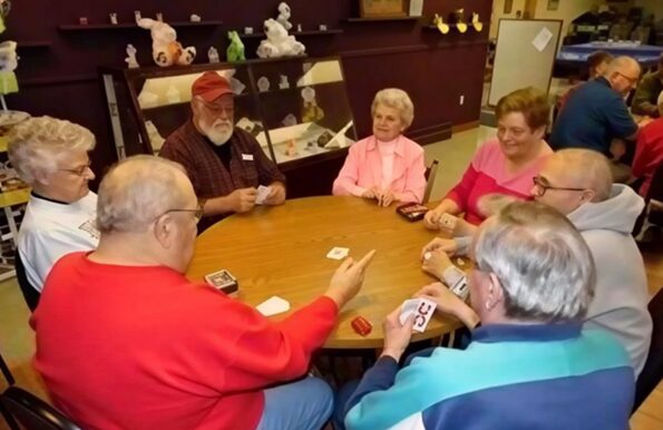 A group of older adults sitting at a table playing cards