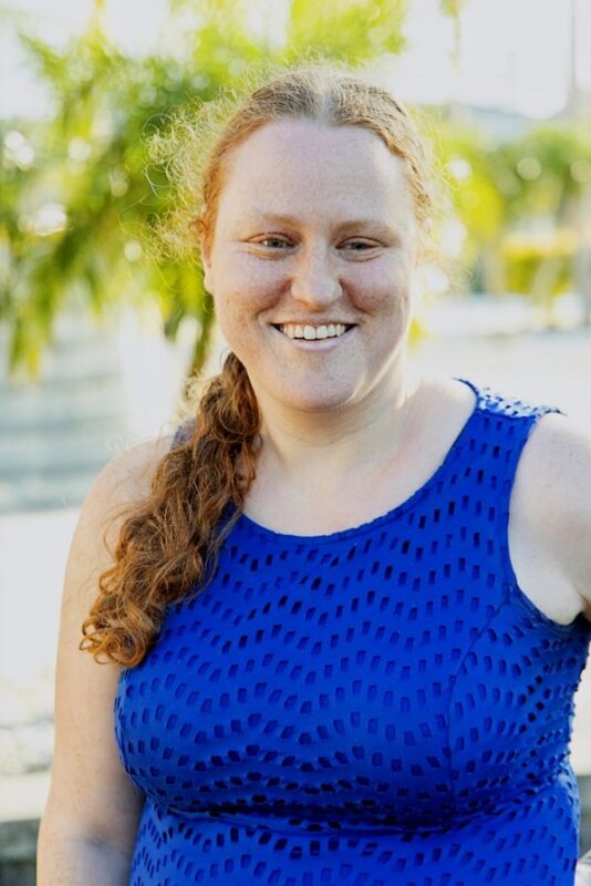 A light-skinned woman with red hair smiling for the camera