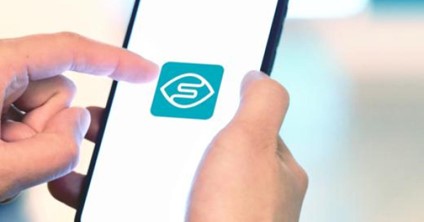 Hands holding a smartphone displaying the Seeing AI app logo
