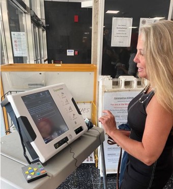 A light-skinned woman using an accessible voting machine