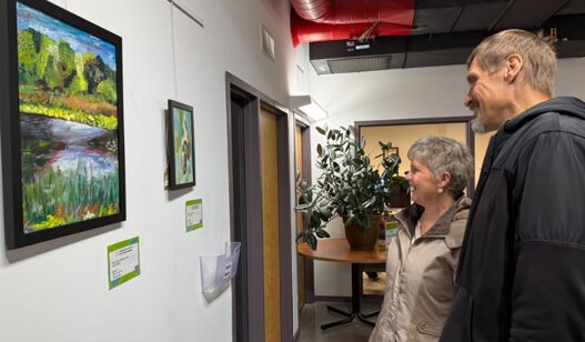 A man and a woman admiring two paintings hanging on a wall