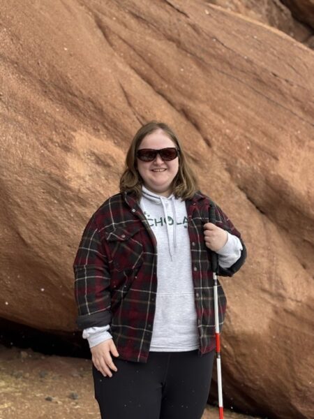 Kaylee Mueller standing in front of a boulder