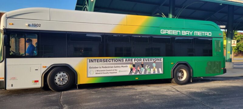 A Green Bay municipal bus, with a graphic on the side that reads "Intersections are for everyone, October is Pedestrian Safety Month"
