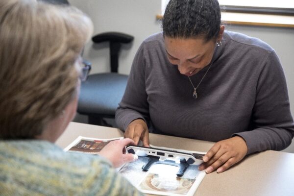 A low vision therapist working with a client using a small digital magnifier