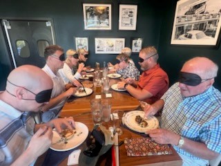 A table of blindfolded diners digging into an appetizer.