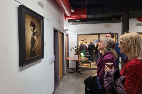 Three people examining a painting hanging on a wall in the Council office.
