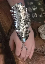 An arm band of silver scales attached at the fingers and forearm, resembling armor