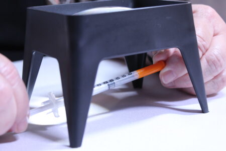 Using a magnifier to help read the markings on a syringe