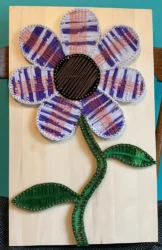 A 3D piece featuring a textile flower mounted on wood