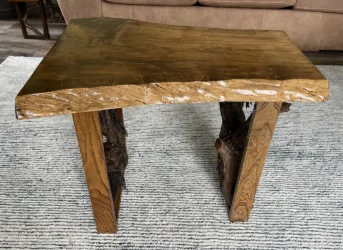 A beautiful grained natural wood slab end table with driftwood mounted in the legs