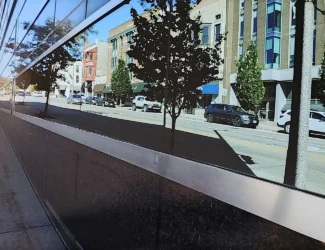 Photo of a city street as reflected in a building’s bottom floor windows.